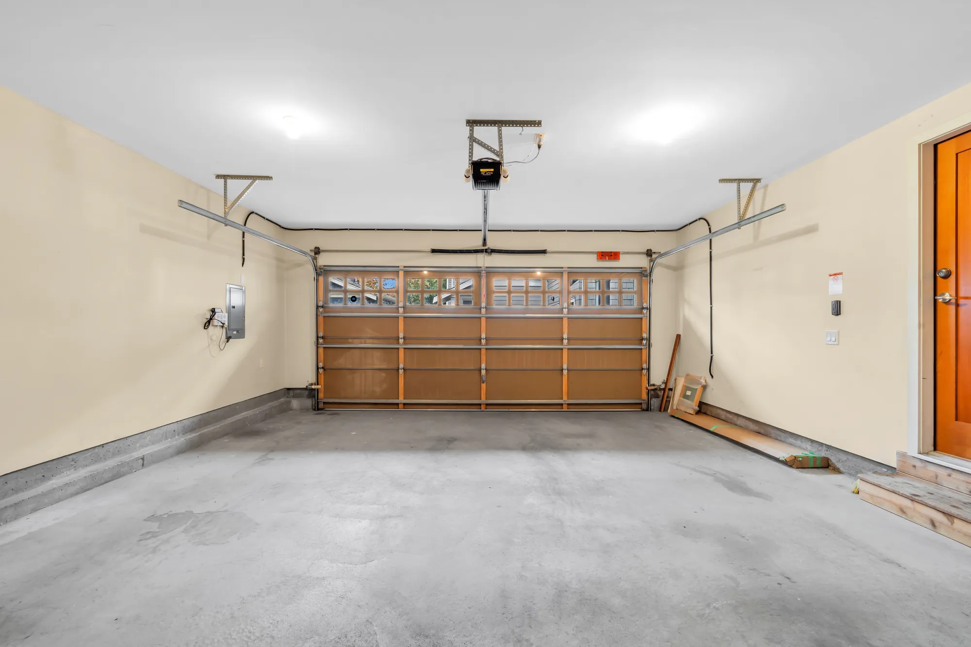 The double garage: a wood-panelled overhead door with a row of windows, an opener, a concrete floor, the door into the house at the right