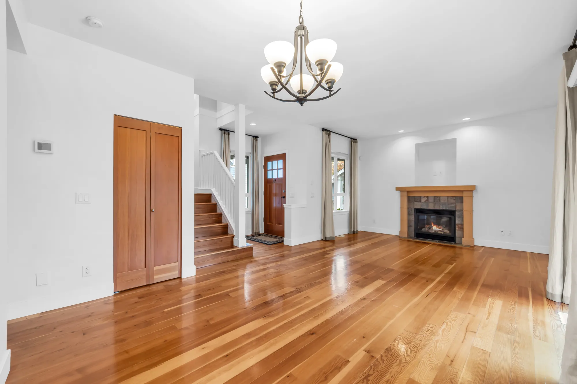 The dining room from the side: a double closet with wood doors, the stair and the front door, the fireplace, a chandelier