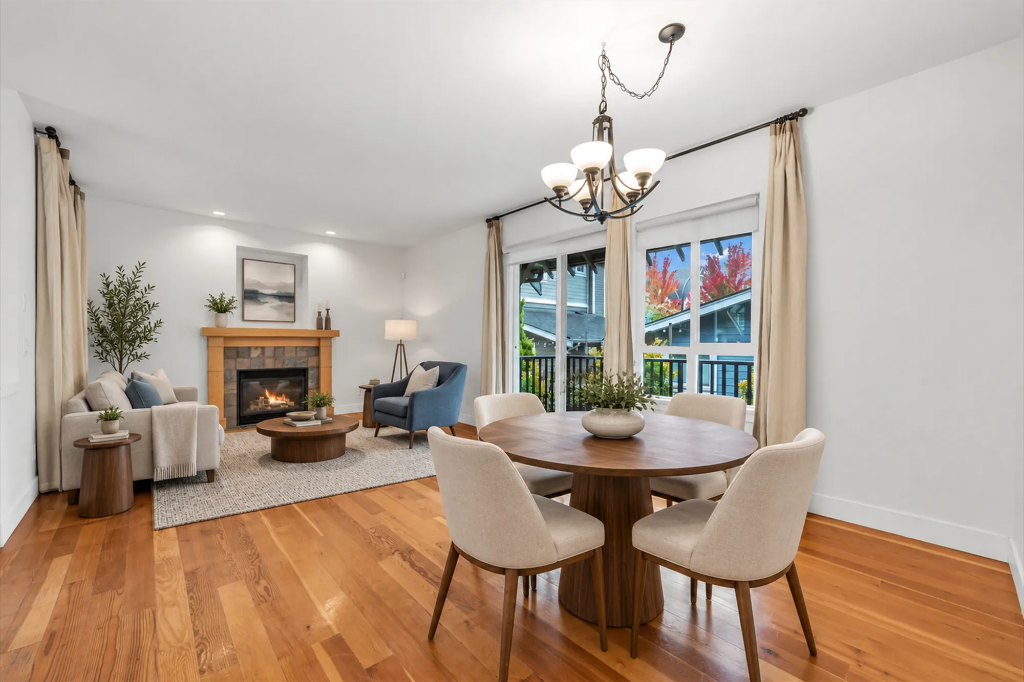 The same frame virtually staged: a sofa, a blue armchair, a round coffee table on a rug, a floor lamp and an olive tree by the fireplace, a print in the niche, a round dining table with four chairs