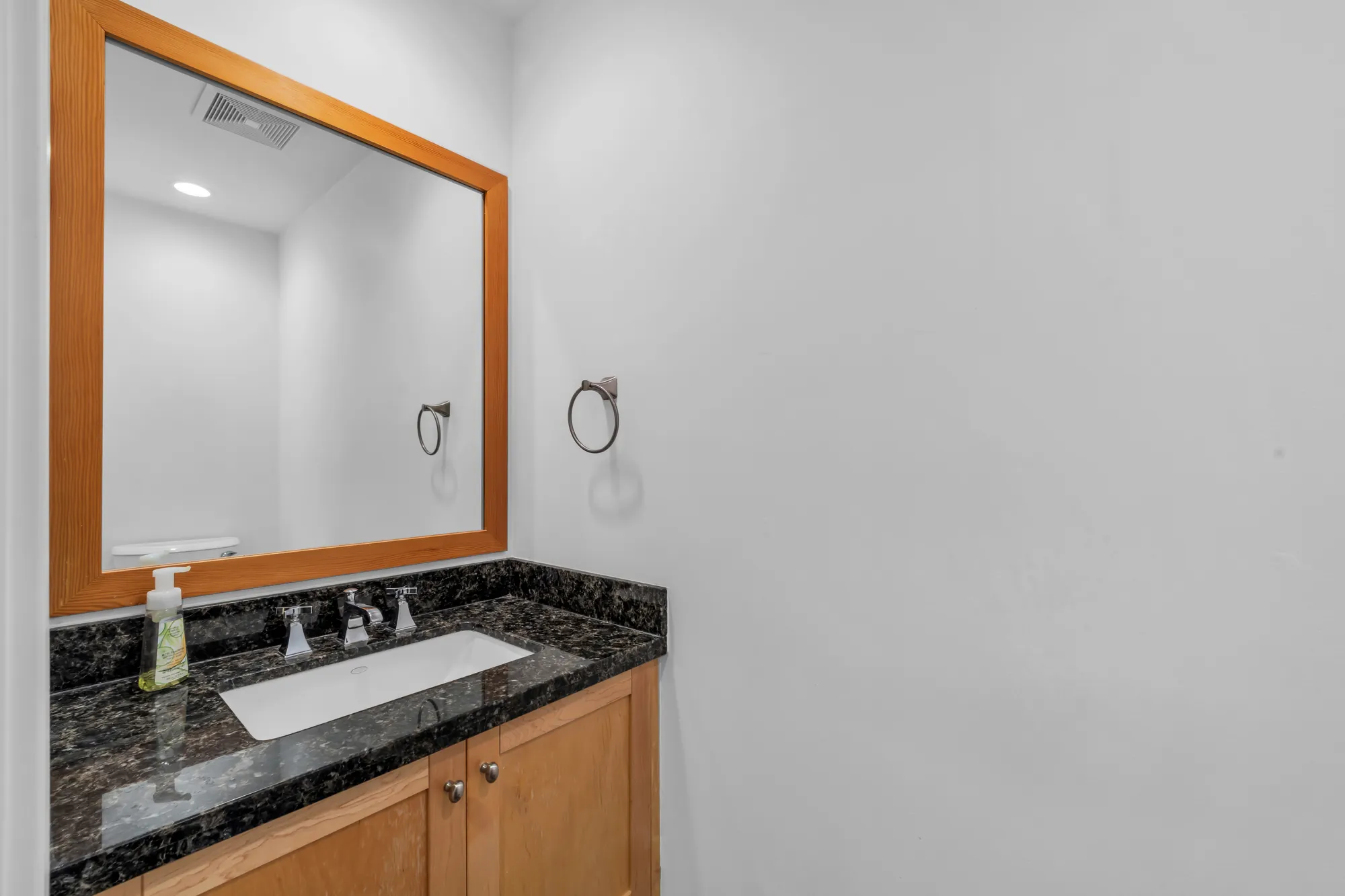 The powder room: a maple vanity with a dark granite top and a wood-framed mirror